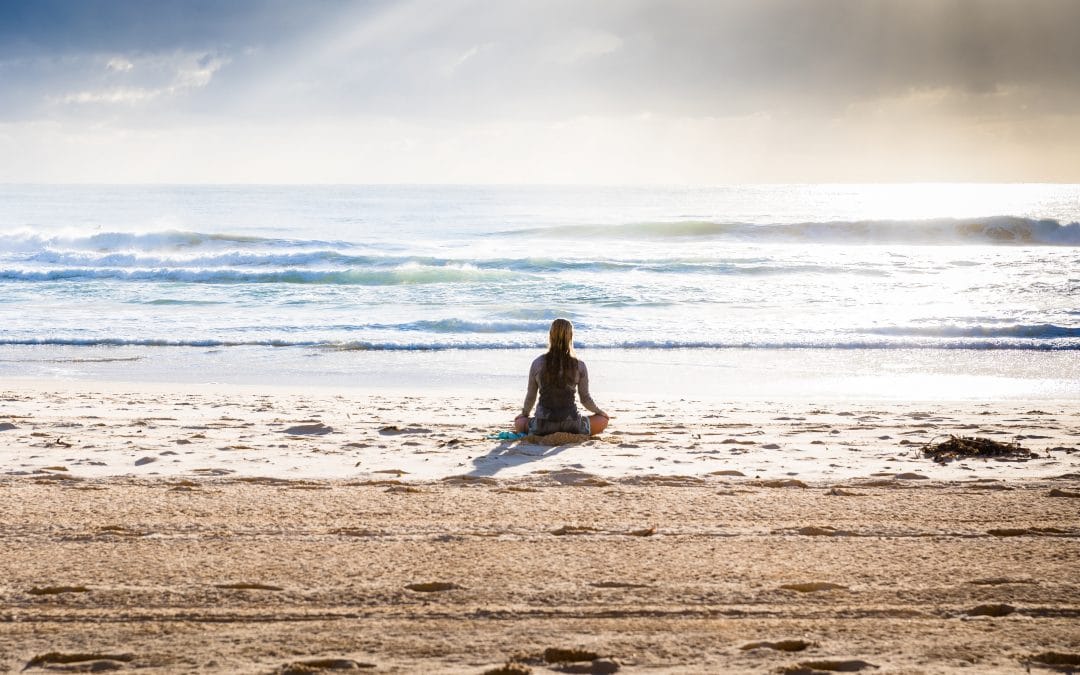 woman meditating at the beach